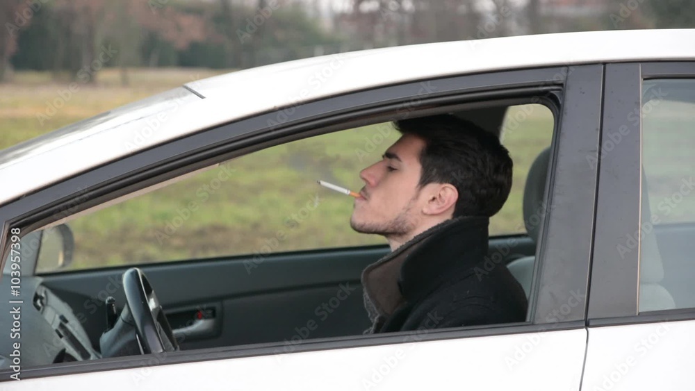 Young Man smoking cigarette while Driving Young Man smoking cigarette while Driving