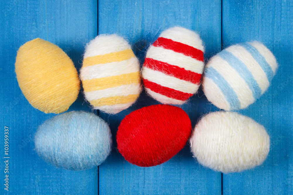 Easter eggs wrapped woolen string on blue wooden boards, decoration for Easter Easter eggs wrapped woolen string on blue wooden boards, decoration for Easter