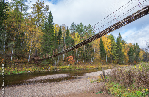 Wooden suspension bridge over the river in the forest