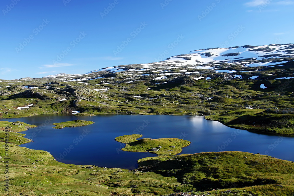 mountain lake and patches of snow in the mountains of Norway