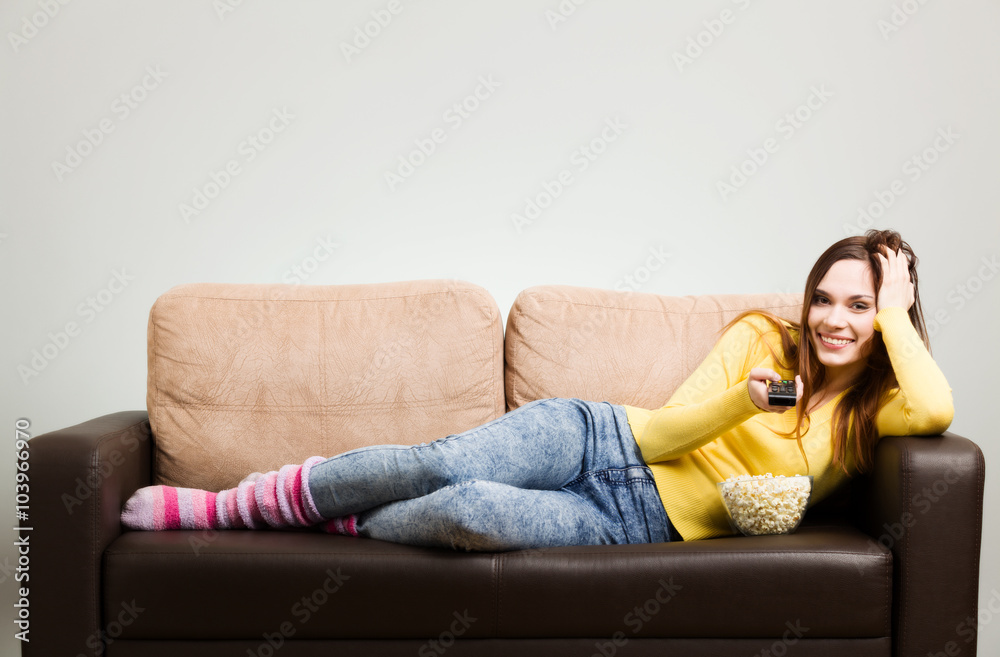 Young woman spends his free time watching TV on the couch at hom Young woman spends his free time watching TV on the couch at hom