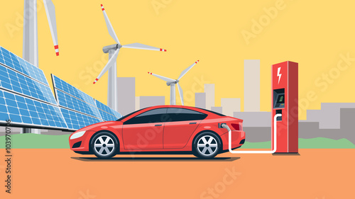 Electric Car Charging at the Charging Station in front of the Solar Panels and Wind Turbines