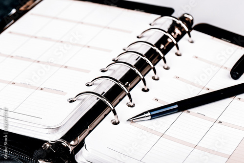 Personal organizer or planner with pen on white background