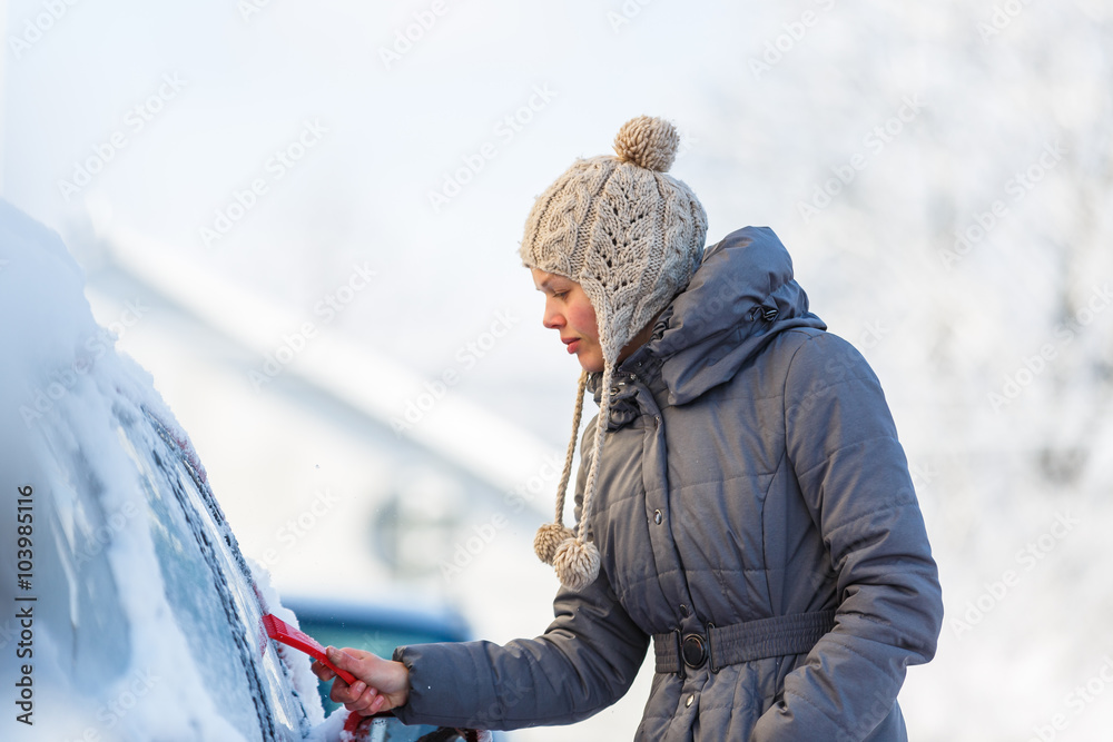 Young woman cleaning her car from snow and frost Young woman cleaning her car from snow and frost