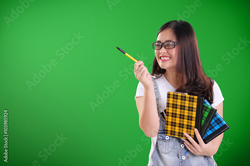 Funny school girl pointing at copy space on green chalkboard