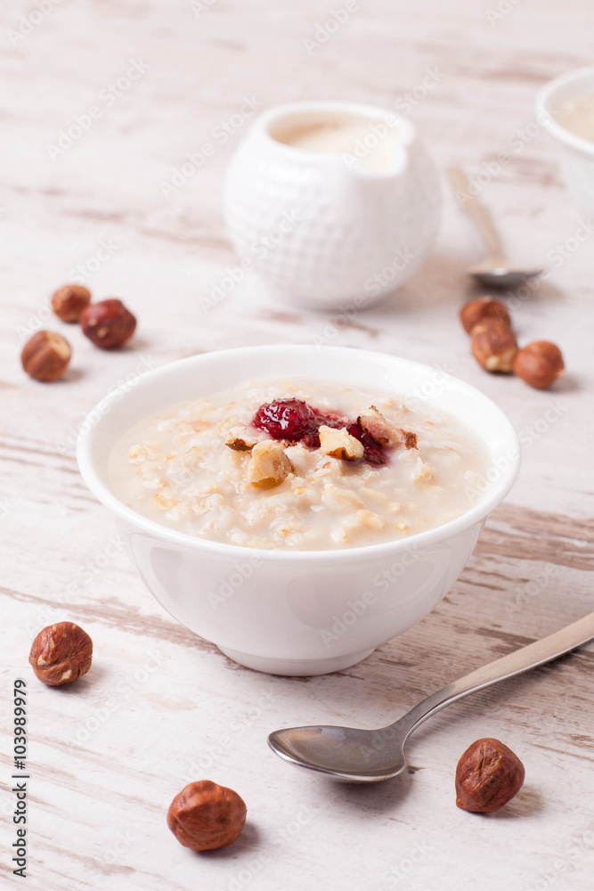 Oatmeal with milk, nuts and strawberry jam and milk jug