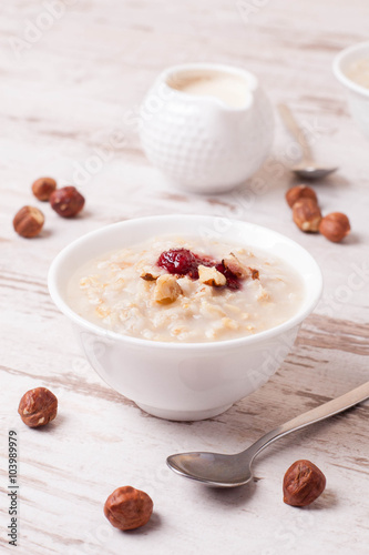 Oatmeal with milk, nuts and strawberry jam and milk jug