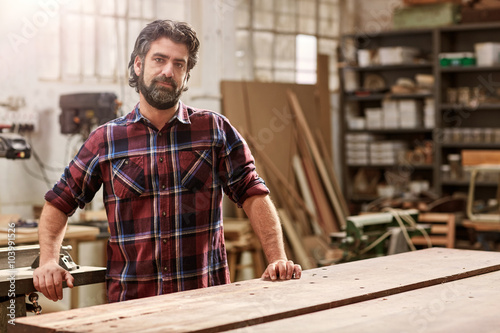 Artisan craftsman with a beard in his woodwork workshop