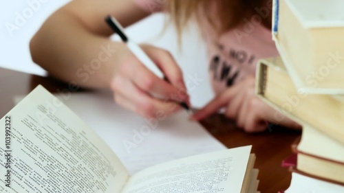 Beautiful girl sitting at the writing desk. Girl preparing for exams.