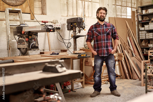 Carpentry business owner standing in his workshop with machinery