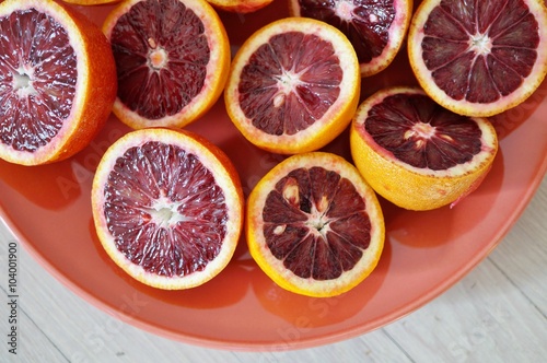 Plate of ruby red blood oranges cut in half on a red platter