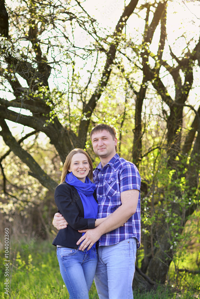 Young couple outdoors in spring, hugs, sunshine, smile Young couple outdoors in spring, hugs, sunshine, smile