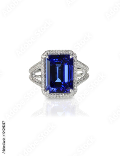 Large emerald cut sapphire blue engagement cocktail fashion ring with halo setting and pave diamonds isolated on white with a reflection