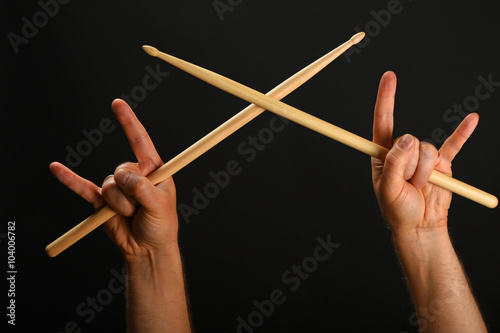 Two hands with crossed drumsticks and devil horns