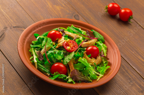 Fresh salad with chicken breast, arugula and tomato. 