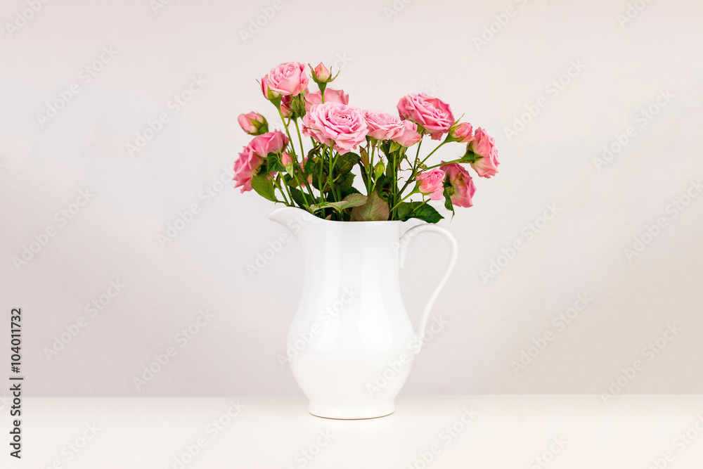 Pink flowers in white jug. Roses in jug.