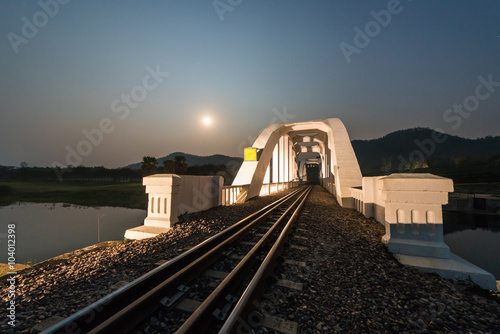 Old white railway bridge constructed against the moon in night a