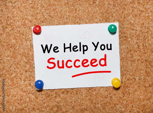 The phrase We Help You Succeed typed on a white piece of note paper and pinned to a cork notice board