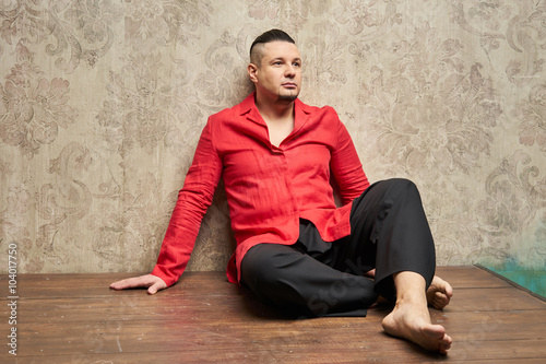 Portrait of a young man, in black slacks and a red shirt, hairst