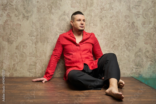 Portrait of a young man, in black slacks and a red shirt, hairst
