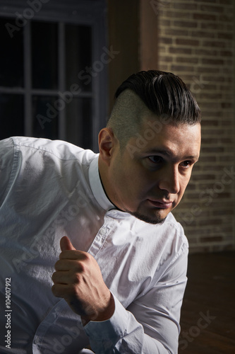 Portrait of young man, black slacks and white shirt, hairstyle with shaved temples and slicked back hair at the head, emotions, black window, Brick wall, beard, skinhead, brutal, evil, killer