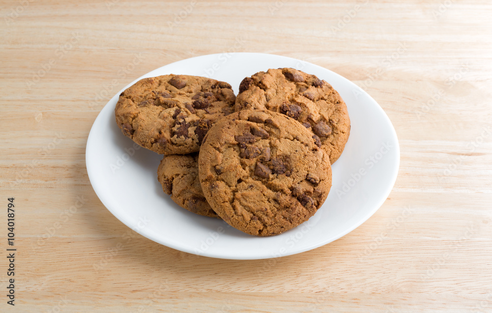 Plate of gourmet milk chocolate chip cookies on a wood table top.