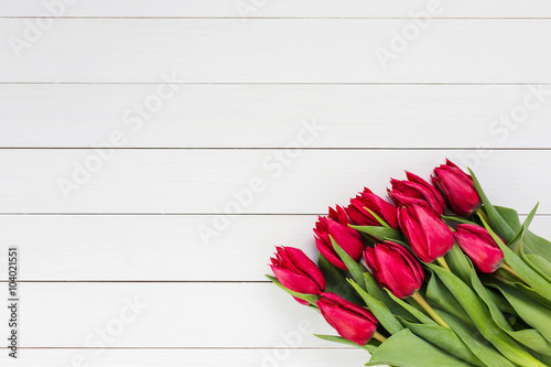 Fototapeta Naklejka Na Ścianę i Meble -  Bouquet of red tulips on white wooden background. Top view, copy space 