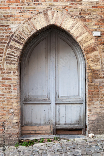 Old gray wooden door with arch in brick wall