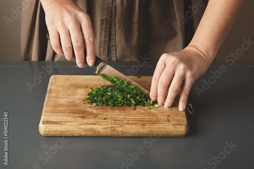 Women hand chop parsley on wooden board