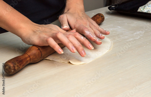 Female hands preparing dough with rolling pin