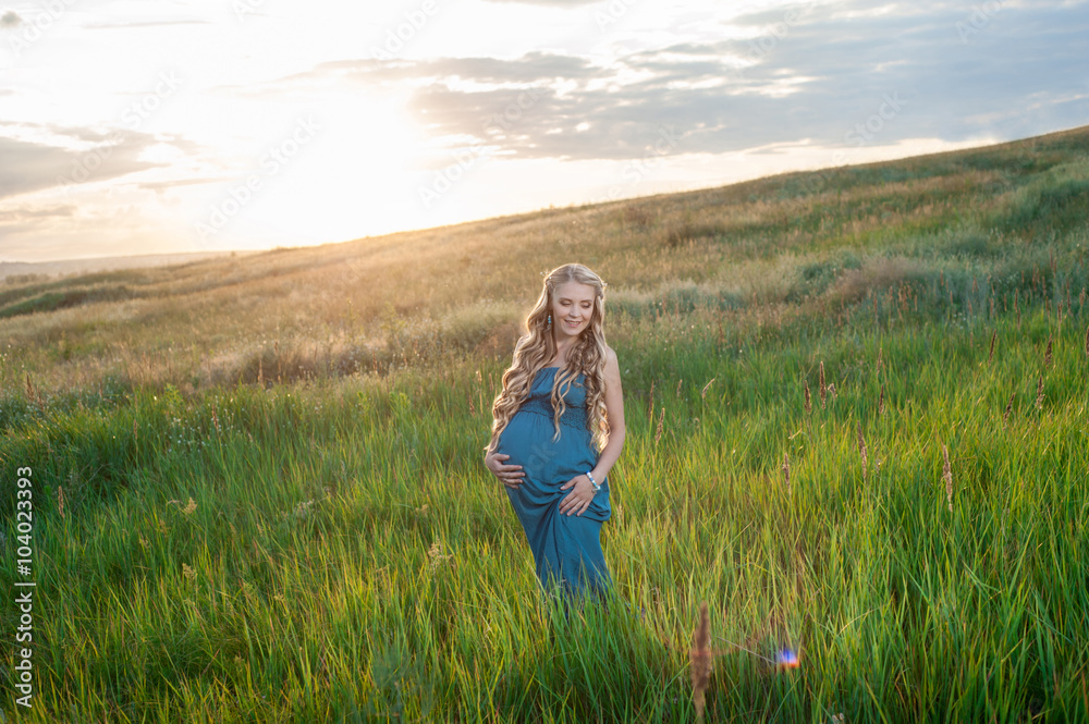 Beautiful tender pregnant woman standing on green grass Beautiful tender pregnant woman standing on green grass