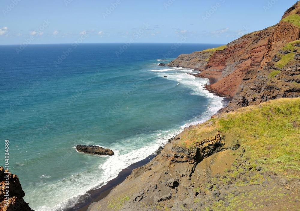 Waves crash on a black sand beach under rugged cliff Waves crash on a black sand beach under rugged cliff