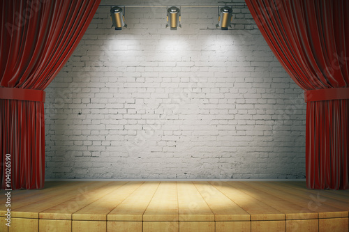 Wooden stage with red curtains and a white brick wall with spotl