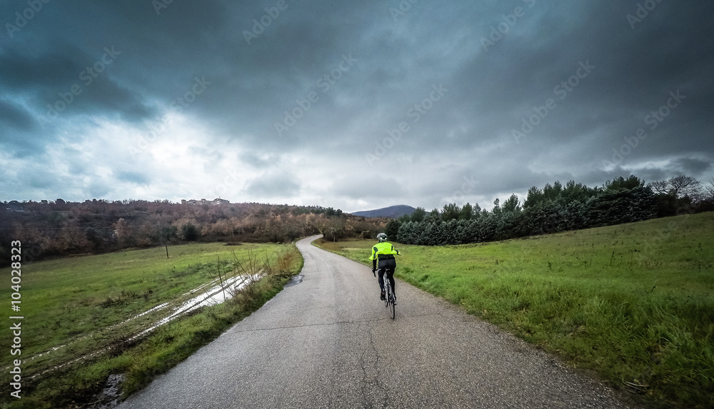 man on a bicycle ride along a mountain road during a storm