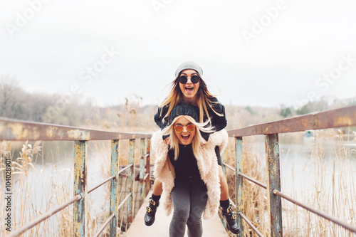 Outdoor lifestyle portrait of two best friends, smiling and having fun together, enjoy each other company posing and making selfie pictures to each other and share happiness
