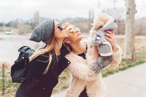 two young caucasian cute girls portrait with dog outdoor in park walking happy and smile all the way
