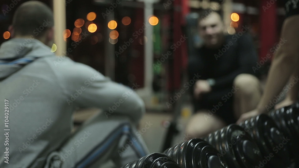 Defocused young guys having rest after workout in the gym, male friends talking Defocused young guys having rest after workout in the gym, male friends talking