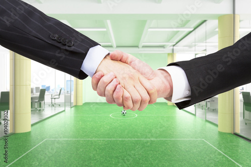 Handshaking of business partners at office footbal field backgro