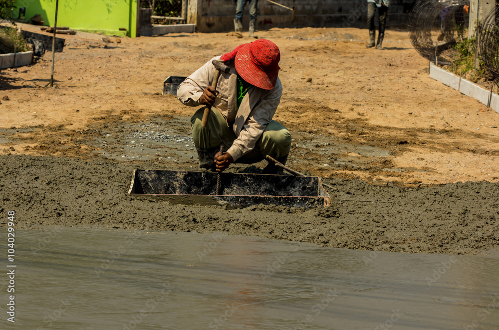 Construction worker spreading wet poured concrete Construction worker spreading wet poured concrete