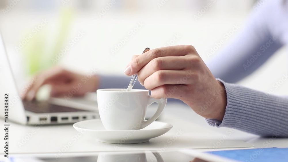 Young woman having a coffee break, she is stirring her espresso and using a laptop, hand close up, seamless loop Young woman having a coffee break, she is stirring her espresso and using a laptop, hand close up, seamless loop