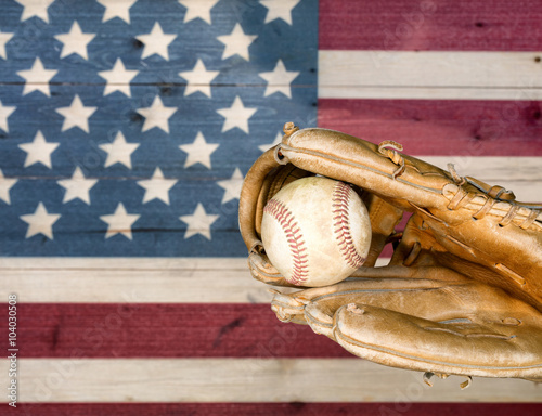 Weathered baseball mitt and ball with faded boards in USA flag colors