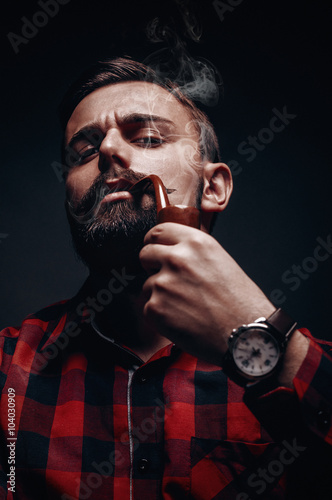 Portrait of proud bearded lumber like man smoking pipe 