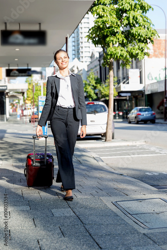 Business woman pulling suitcase bag walking in city