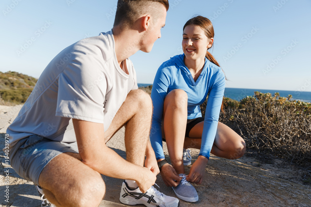 Couple of runners lace their shoes and prepare to jogging Couple of runners lace their shoes and prepare to jogging