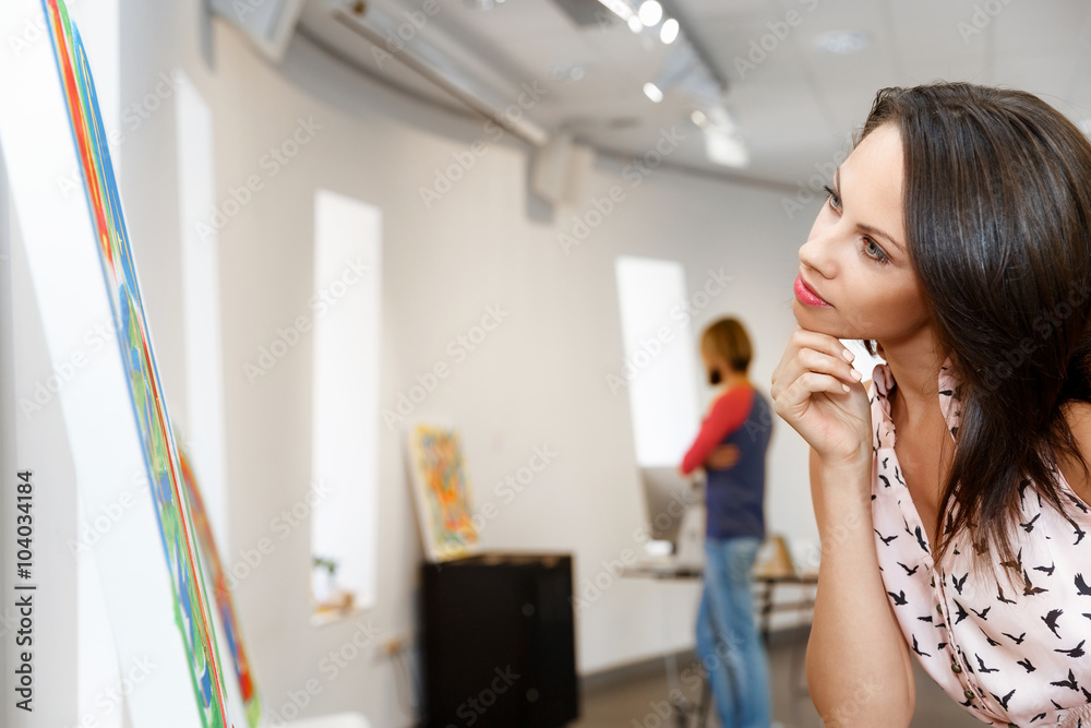 Young caucasian woman standing in art gallery front of paintings Young caucasian woman standing in art gallery front of paintings