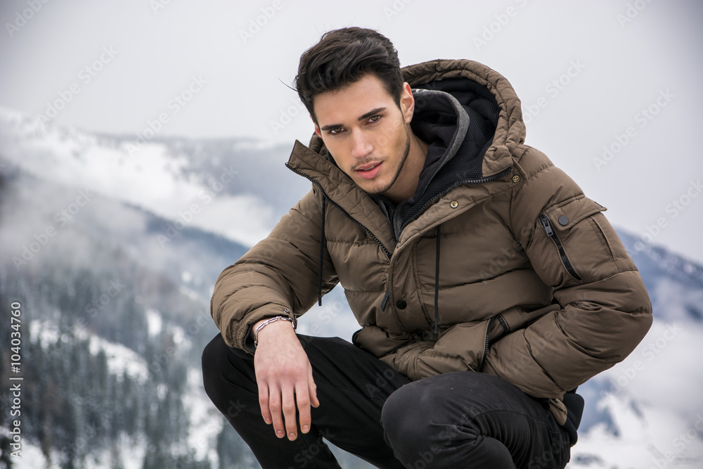 Man in outerwear sitting while looking at camera