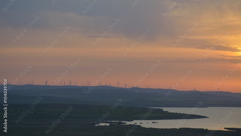 Silhouettes of wind turbines during sunset