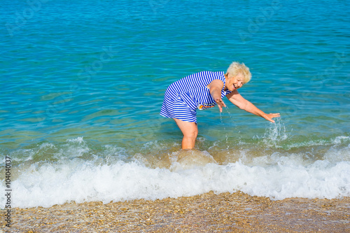 Fotografie Happy elderly woman enjoying on the beach