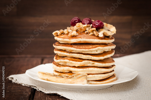 Pancakes with cherries, grilled banana and nuts on a dark background