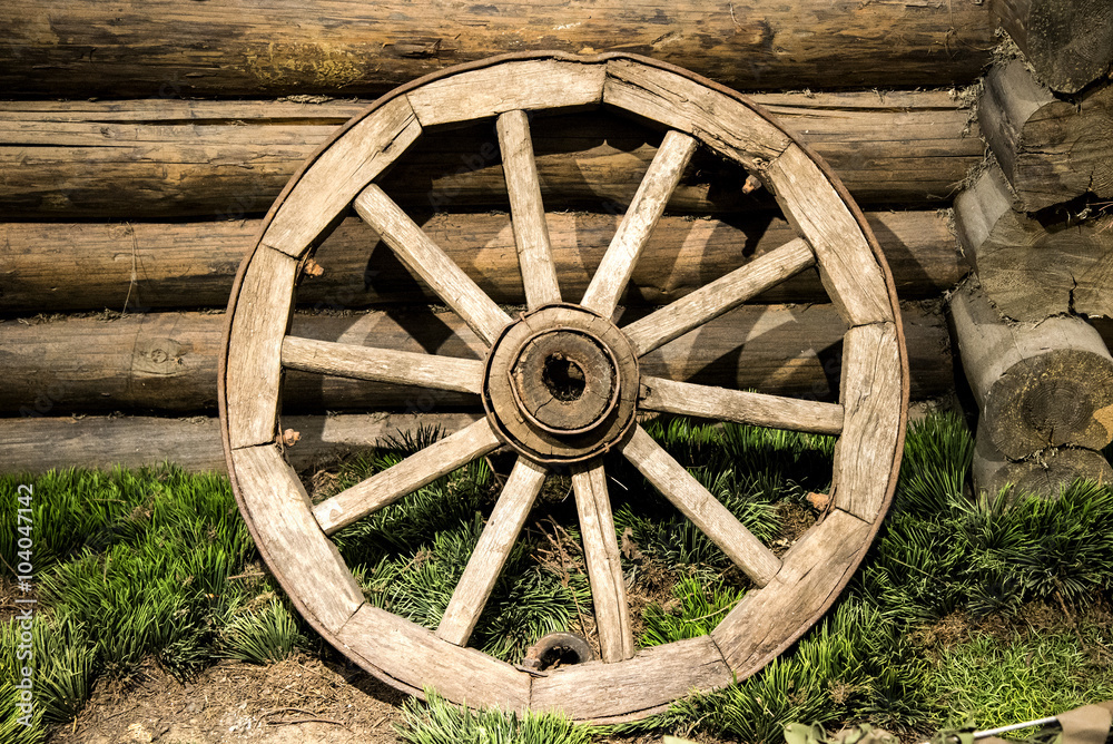 Old wooden coach wheel near barn